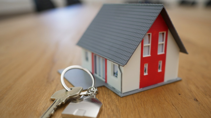 Miniature House with Red Trim next to house keys
